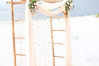 23 a cool bamboo wedding arbor with flowy fabric, blush and white blooms, greenery and rhinestones hanging down