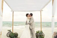 26 a wedding chuppah of bamboo topped with white fabric, tropical leaves and wicker balls on the floor