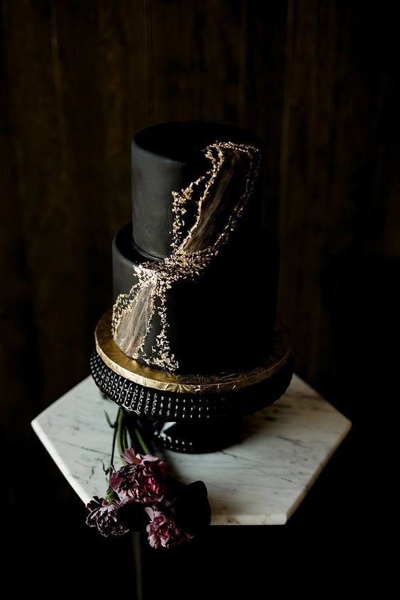 an edgy black wedding cake with gold foil and marble detailing for a modern wedding