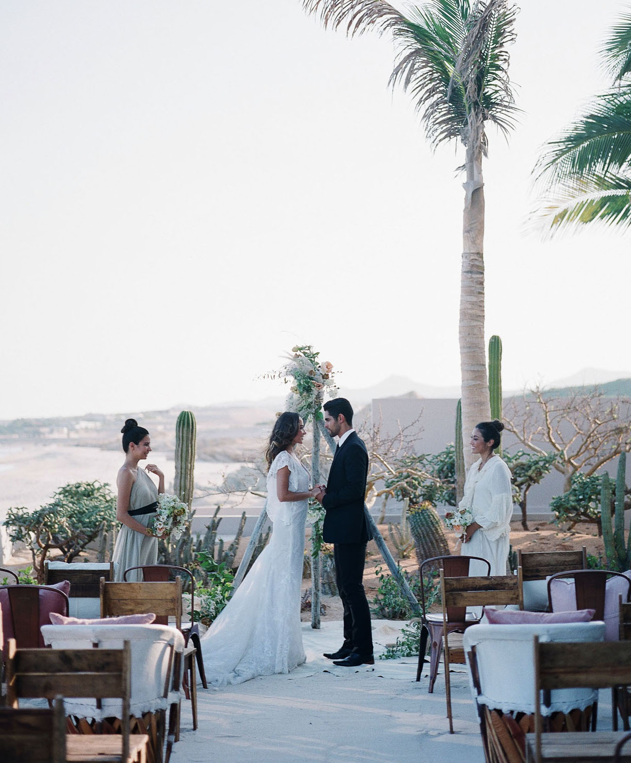 The ceremony space was a boho one, with mismatching chairs, a triangle arch, cacti and a gorgeous beach view