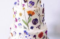 08 a pure white wedding cake all decorated with edible blooms looks wild and very chic
