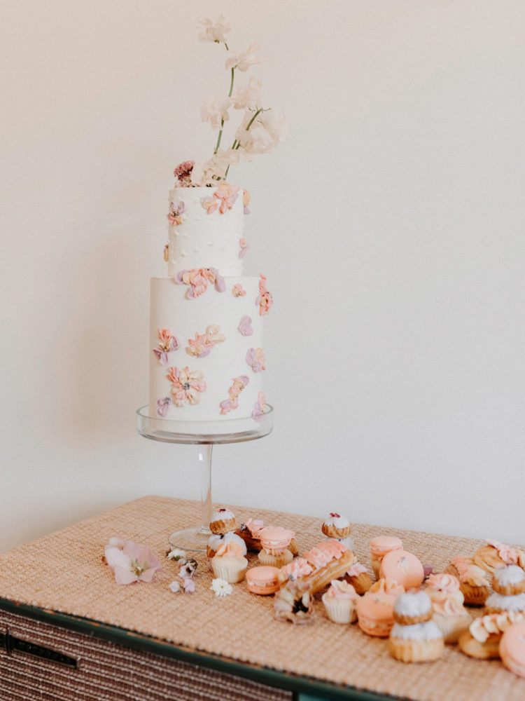 The wedding cake was decorated with peachy pink and lilac sugar flowers and macarons and eclairs were placed right on the table