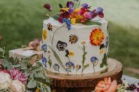 10 a small wedding cake with colorful pressed blooms and some fresh flowers on top