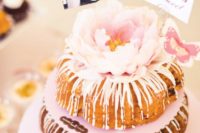 19 a pink glazed cake with a large fresh bloom on top, a photo and a topper for a backyard shower