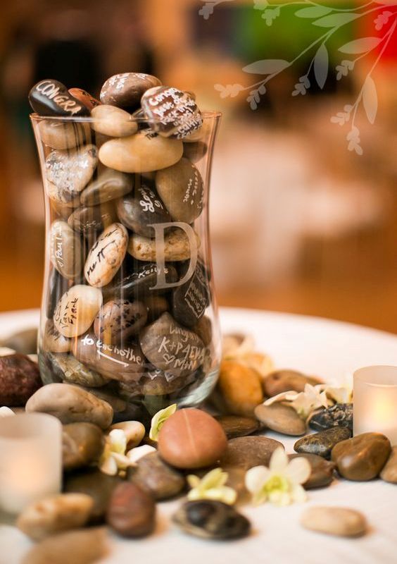 a rustic wedding guest book - lots of pebbles gathered by the couple and signed by the guests