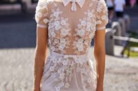 a catchy wedding dress with a sheer bodice and semi sheer skirt, strategically placed lace applique and puff sleeves, a collar