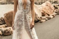 a naked wedding dress with a deep plunging neckline, lace applique all over, straps and an embellished belt for a daring bride