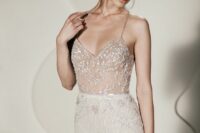 a refined modern wedding dress with a sheer bodice with embellishments and an embellished skirt plus spaghetti straps
