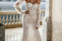 a strapless wedding dress with a lace embellished bodice and a sheer skirt with embellishments and lace plus long sleeves