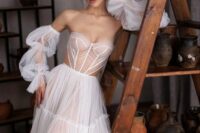 a unique strapless wedding dress with a sheer corset bodice and a layered skirt, some lseeves and side cutouts