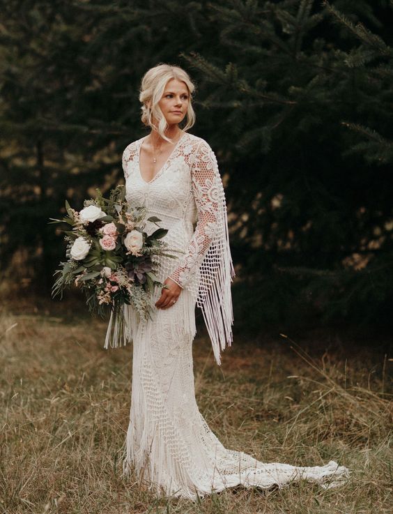 a boho lace sheath wedding gown with a V necckline, a train and fringe on the sleeves