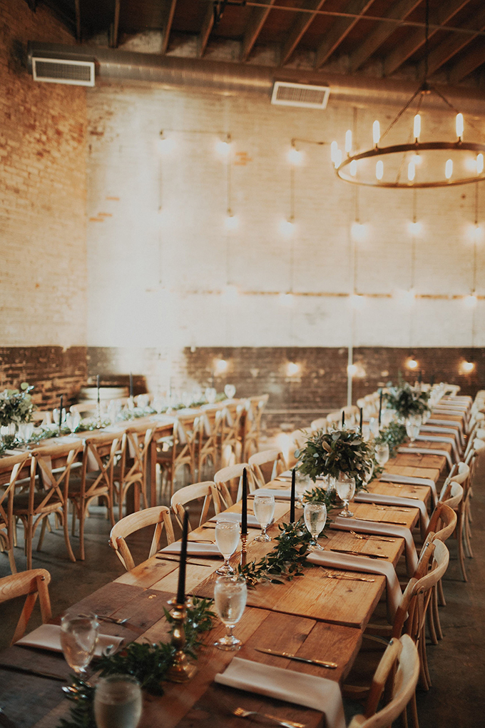 The reception space was done with uncovered long wooden tables, lush greenery centerpieces and black candles