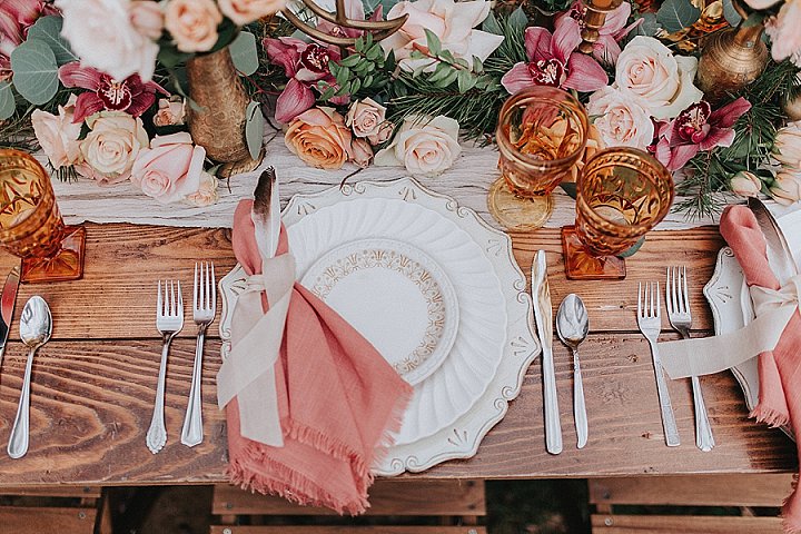 Exquisite chargers, coral napkins with feathers and amber glasses finished off the look