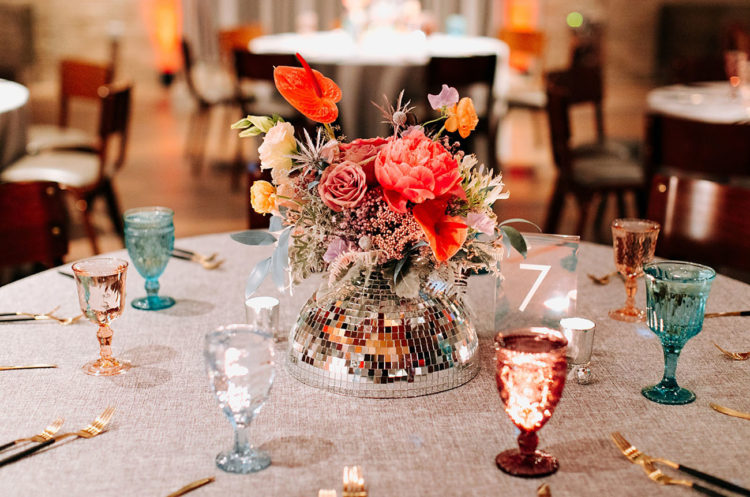 The wedding tablescape was done with various glasses, a disco ball centerpiece and bright blooms