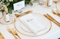 10 The wedding tablescape was neutral, with gold cutlery, with a greenery and white bloom table runner plus olive oil favors
