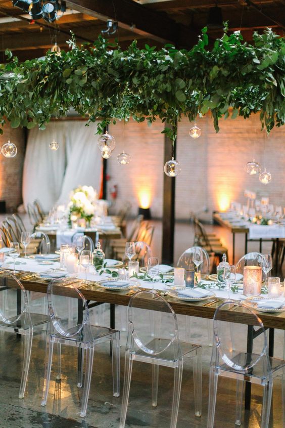 a lush greenery installation with hanging bubbles and candles is a very refreshing idea for an indoor wedding