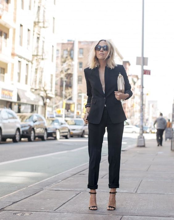 a black pantsuit with no top under, a metallic bag and black heels for a sexy look