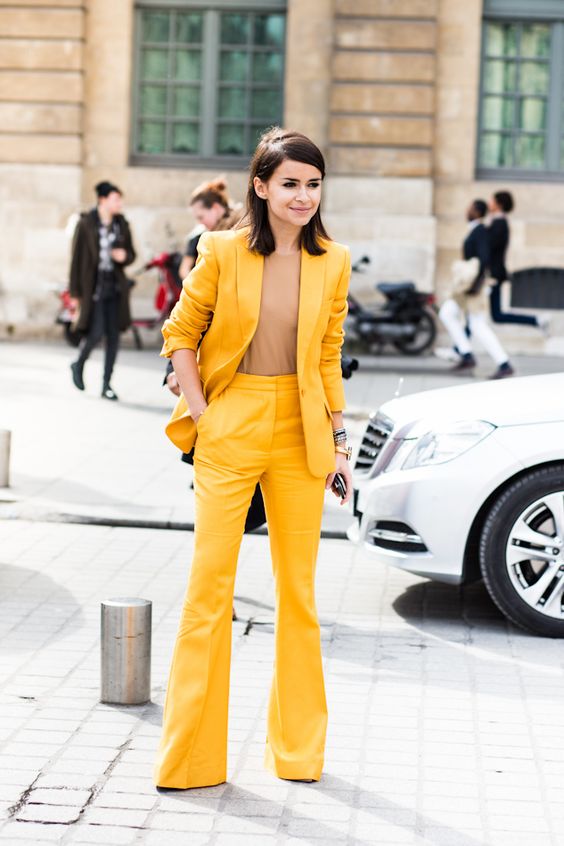 a bright yellow suit with flare pants, a camel top that matches the skin and a small clutch
