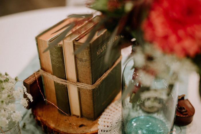 a vintage book wedding centerpiece on a wooden slice is a cool idea for a book-loving wedding