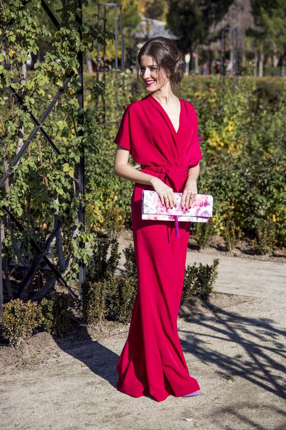 a bright fuchsia jumpsuit with wideleg pants, a V-neckline and ties plus a bright floral clutch