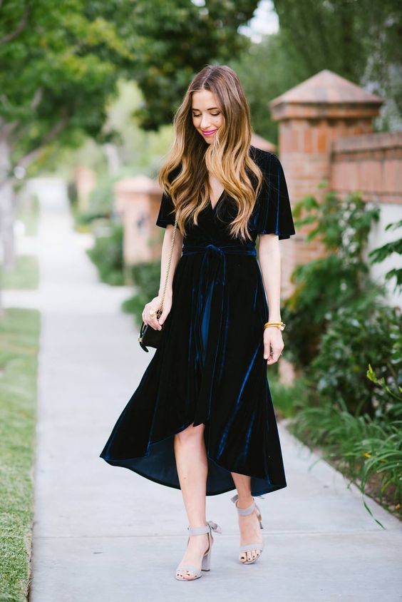a navy velvet wrap midi dress with short sleeves and an asymmetrical skirt, light blue shoes and a black bag
