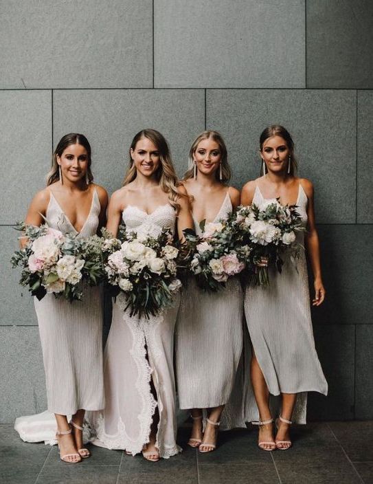 shiny silver high low midi bridesmaid dresses with thick straps and pluning necklines and statement earrings