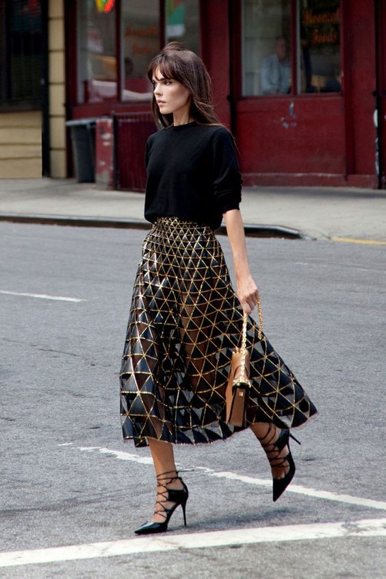 a black oversized sweater, a blakc and gold geometric midi skirt, black lace up shoes and a camel bag