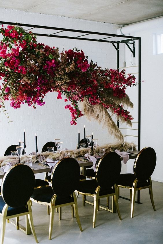 a suspended bougainvillea floral and pampas grass overhead centerpiece for a modern chic wedding reception