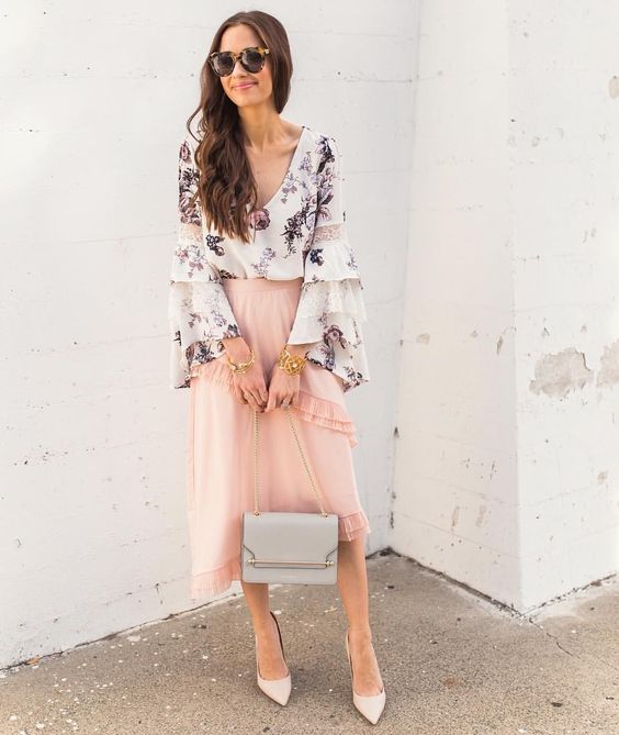 a blush ruffled asymmetrical midi, a floral blouse with bell sleeves, neutral shoes and a grey bag