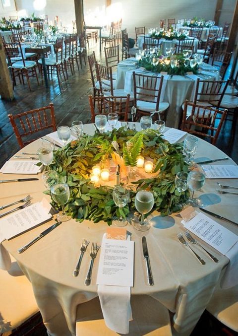 a greenery table centerpiece with eucalyptus, ferns and candles is a unique wreath-like piece