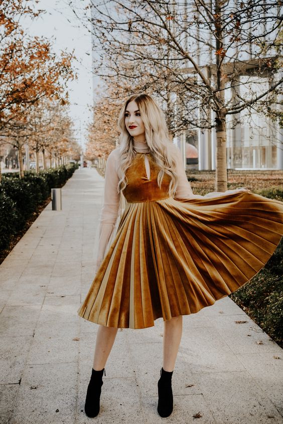 a mustard velvet A-line dress with a halter neckline and a pleated skirt is perfect for a spring wedding guest look with black booties for a fall wedding