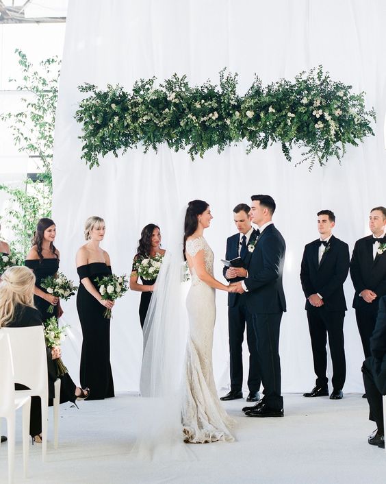 an overhead greenery and white bloom wedding installation as a wedding ceremony backdrop