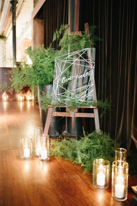 acrylic wedding signage with much fern around and pillar candles for a modern wedding