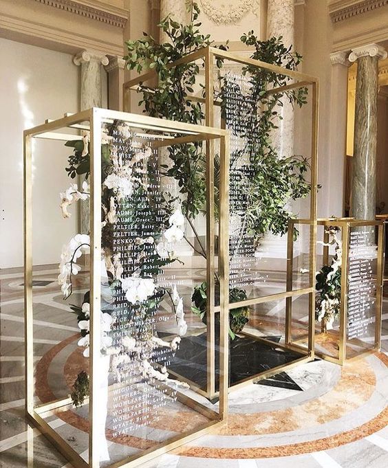 floral and greenery installations in gilded frames with wedding signage is a modern adn fresh idea of a seating chart