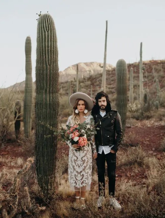 a boho groom's look with a white shirt, black jeans, a black leather jacket and neutral sneakers is a lovely idea for a desert wedding