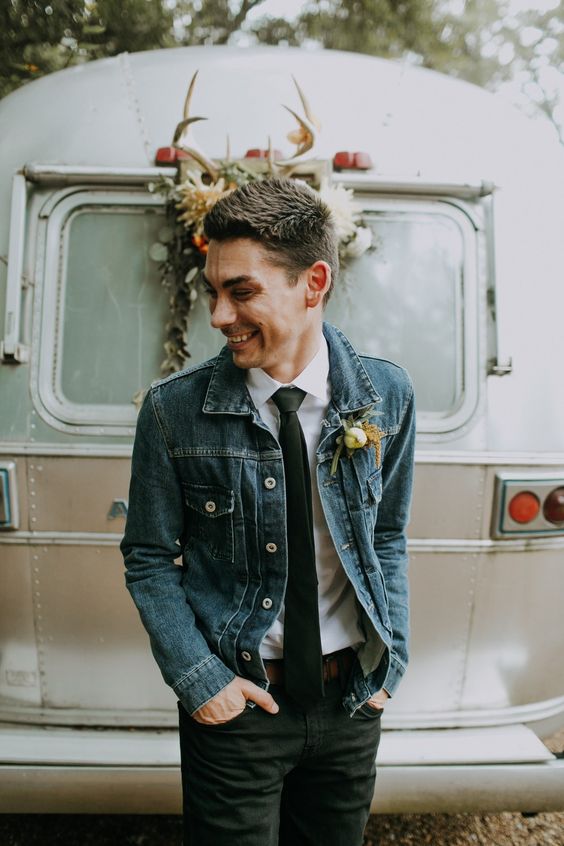 a relaxed boho groom's look with black jeans, a blue denim jacket, a white shirt and a black tie is coo, easy and fun