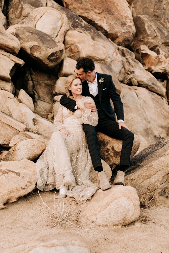 a black plaid three-piece wedding suit with a white shirt and no tie plus tan boots to walk in the desert