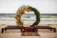 04 The wedding ceremony space was done with benches, boho rugs and a large circle wedding arch of pampas grass and greenery