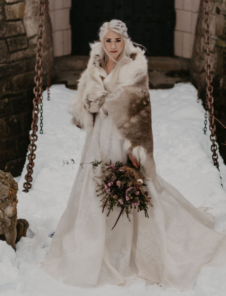 Daenerys-styled bride in a lace wedding ballgown, with a braided hairstyle and a fur coverup