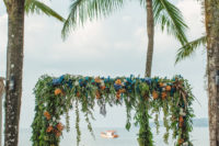 05 The wedding arch was created almost on the beach, it was decorated with greenery, bright rust and blue blooms