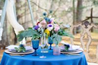 06 The wedding table setting was done with a bright blue tablecloth and glasses, a colorful floral centerpiece, lavender napkins and pink glasses