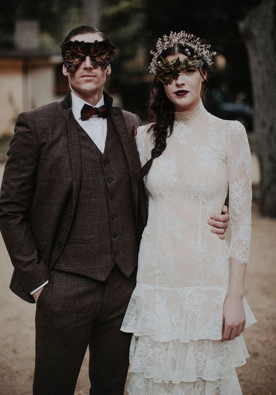 a brown checked tweed three-piece suit, a white shirt, a burgundy bow tie and a unique mask for a Halloween groom