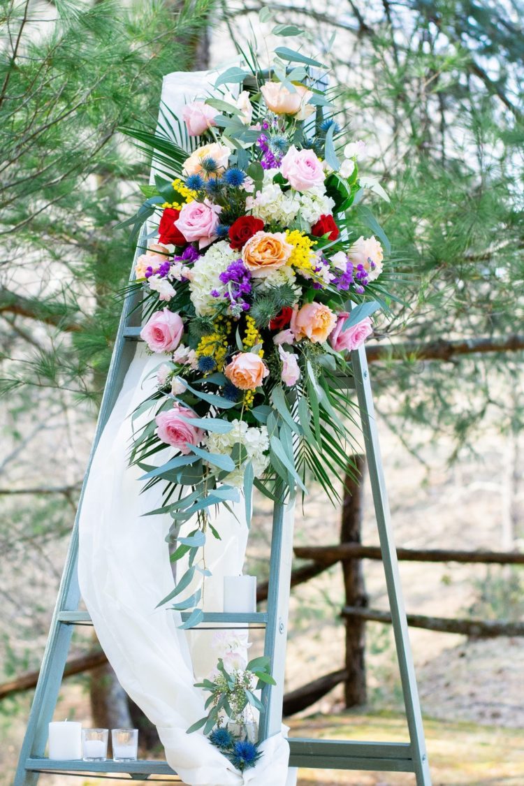 The wedding decor was done with a ladder, colorful blooms, candles and airy fabric