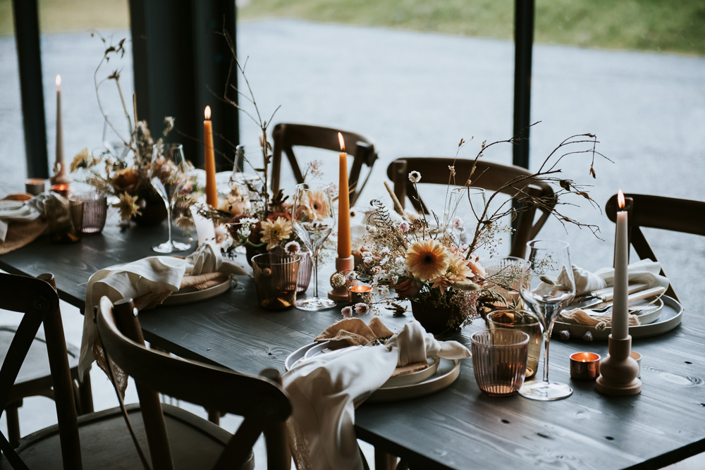 The wedding tablescape was done in earthy tones, with rust candles, dried herbs and blooms, colored glasses and neutral napkins