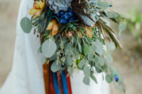 09 The wedding bouquet was done with lots of greenery, rust and blue flowers, succulents and even peacock feathers