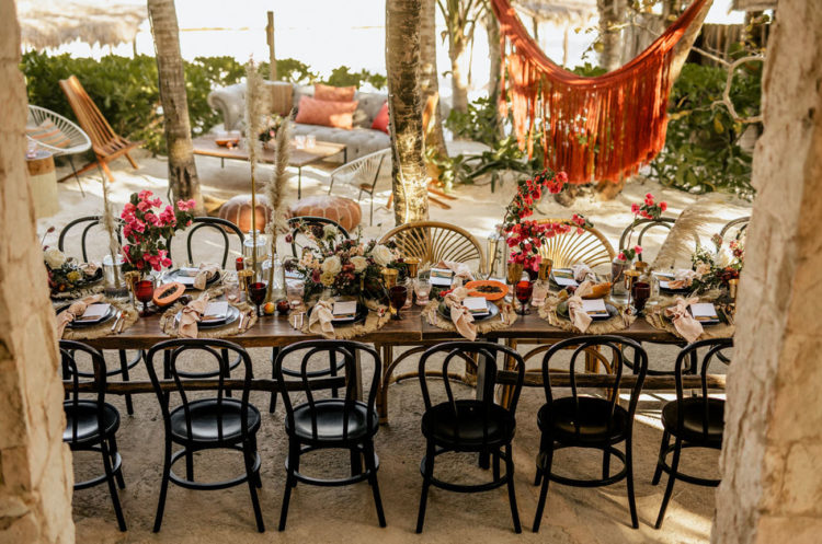 The wedding tablescape was done with bright florals, tropical fruits, fringe and colorful glasses