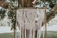 09 a relaxed summer wedding backdrop of macrame and some greenery and pink blooms hanging on one side