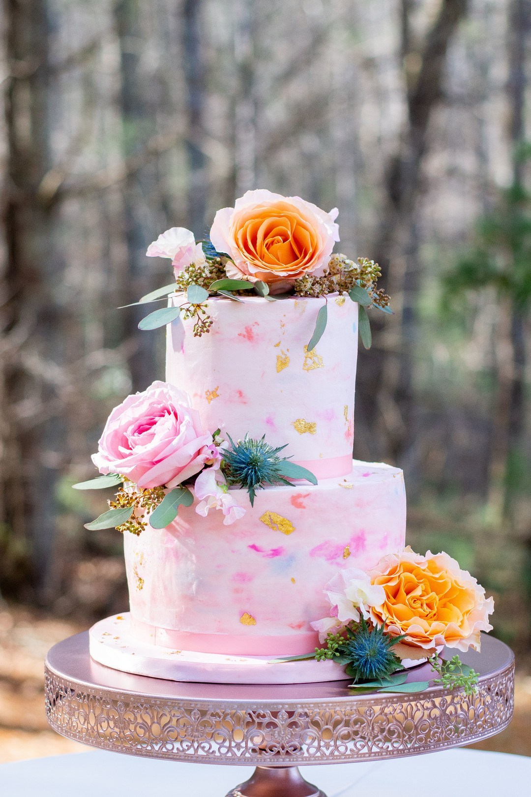 The wedding cake was a pink one, with watercolor brushstrokes in bold colors and gold leaf plus bright blooms and thistles