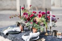 10 a lush and bold wedding table setting with a black tablecloth, a bright floral centerpiece and copper mugs