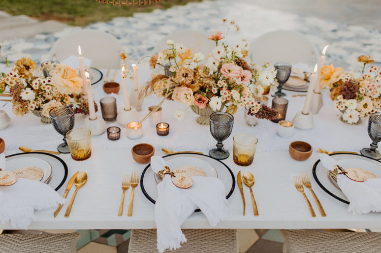 The wedding tablescape was done with lush neutral, rust and pink florals, gold cutlery, amber glasses and candles